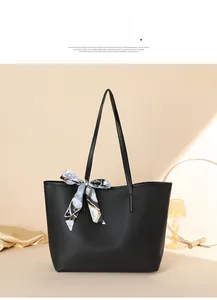 Detail of black pebbled leather tote bag featuring a decorative blue silk scarf on strap