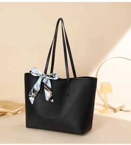 Detail of black pebbled tote bag with elegant blue silk scarf on a warm beige background