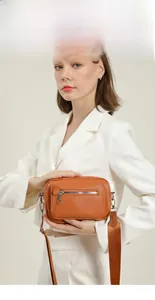 Brown leather crossbody bag detail with silver front zipper and adjustable nylon strap