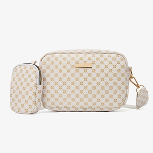 Detail of cream crossbody bag set with gold floral patterns and metal hardware