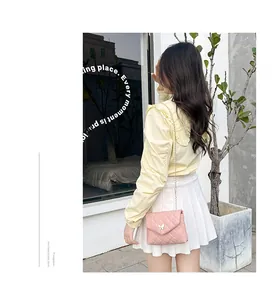 Détail de la pochette rose matelassée avec fermoir papillon doré et bandoulière en chaîne
