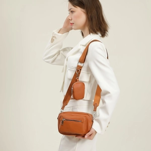 Caramel brown leather crossbody bag with small pouch shown on white blazer outfit