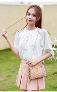 Close-up of beige quilted crossbody bag with gold chain strap and deer charm pendant