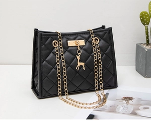 Detail of black quilted shoulder bag with golden chain and small deer pendant charm