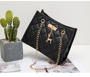 Detail of quilted black shoulder bag with gold chain strap and deer pendant charm