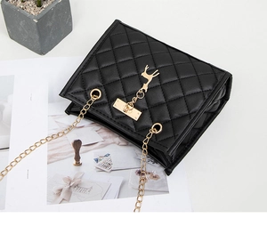 Close-up of black quilted shoulder bag with golden deer charm and metal lock detail
