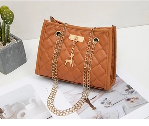 Detail of a brown quilted leather shoulder bag with golden chain and deer pendant