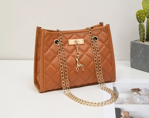 Detail of brown quilted shoulder bag with gold deer charm and dual chain straps