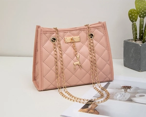 Close-up of pink quilted crossbody bag featuring a golden deer charm and chain strap