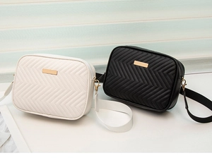 Detail of V-shaped quilted crossbody bags in black and white with gold metal accents
