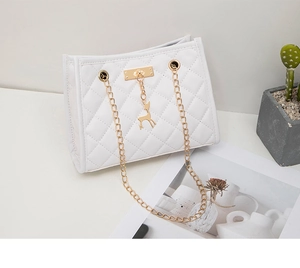 Detail of white quilted crossbody bag featuring gold chain and deer charm ornament