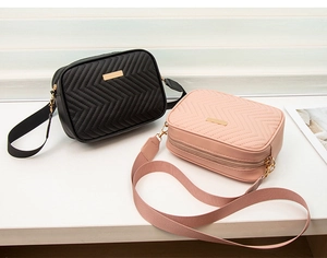 Detail of square crossbody bags in black and pink with herringbone quilting and wide straps