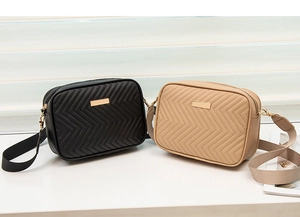 Detail view of quilted black and beige camera bags with golden plates and wide straps