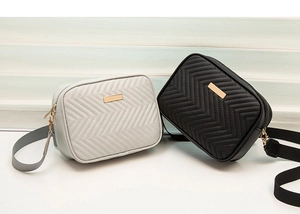 Close-up of chevron-quilted crossbody camera bags in black and gray with metal hardware