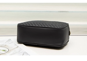 Detail view of black quilted crossbody camera bag with elegant zigzag stitching patterns
