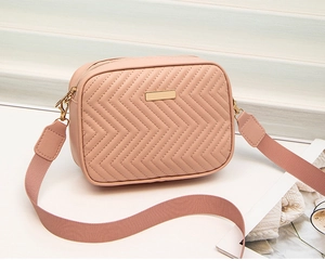 Detail of pink quilted crossbody bag with golden metal hardware and wide woven strap