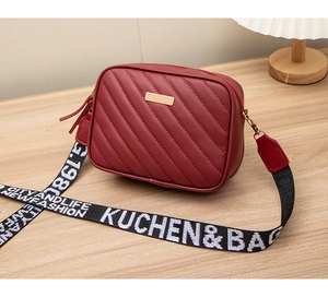 Detail der roten gesteppten Umhängetasche mit Doppelreißverschluss und Jacquard-Gurt
