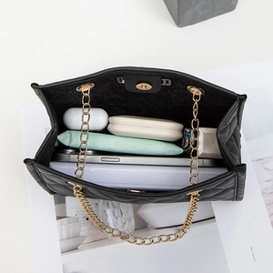 Quilted black shoulder bag with gold chain strap and deer charm showing interior storage