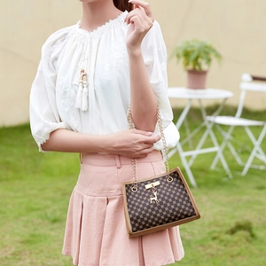 Brown monogram chain shoulder bag with gold deer pendant in outdoor setting