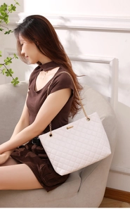 Detailed view of white quilted shoulder bag with golden chain strap and metal clasp