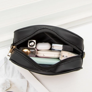 Minimalist black embroidered camera bag with wide strap showing spacious inner storage