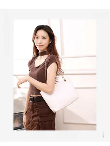 Close-up of white quilted shoulder bag with gold chain strap and metal buckle detail