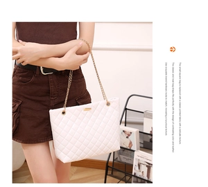 Close-up of white quilted tote bag with gold chain straps and metal buckle detail