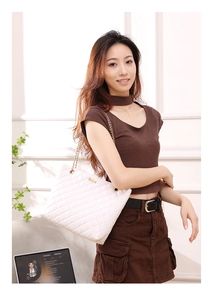 Detail view of a white quilted bucket bag with golden chain strap on a model's shoulder