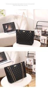 Detail of black quilted tote bag with gold chain straps and metallic plate accessory