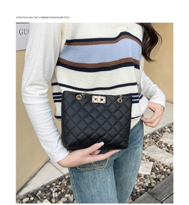 Detail of black quilted shoulder bag with gold chain strap and metallic twist lock