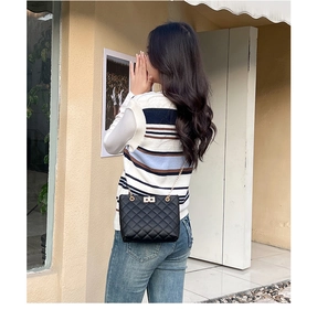 Detailed view of black quilted crossbody bag with gold chain strap and metal lock closure