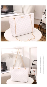 Detail of white quilted tote bag featuring golden chain strap and metallic buckle