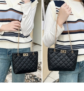 Detail showing the quilted faux leather texture and gold chain strap of the black bucket bag