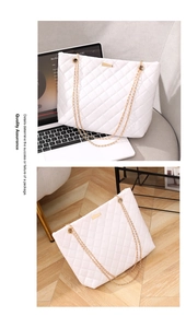 Detail of white quilted tote bag with gold chain straps and rectangular metal plaque