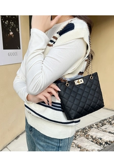 Detail of black quilted shoulder bag featuring a gold twist lock and elegant chain strap