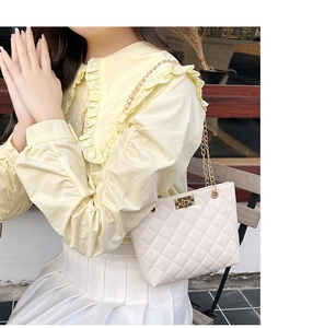 Close-up of ivory quilted shoulder bag with gold twist lock and metal chain strap