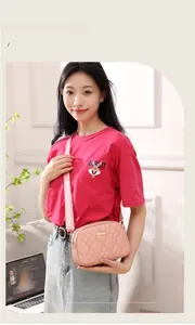 Detail view of pink quilted crossbody bag with gold metal buckle and wide strap