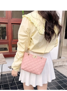 Close-up of pink quilted crossbody bag featuring a gold chain and twist-lock closure