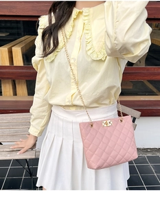 Pink quilted shoulder bag with gold chain strap and turn-lock closure on outdoor model