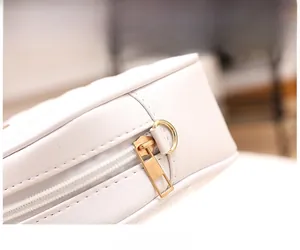 Close-up of white quilted leather bag with smooth golden metal zipper and hardware