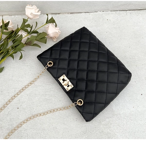 Close-up of black quilted shoulder bag with gold metal twist lock and chain strap