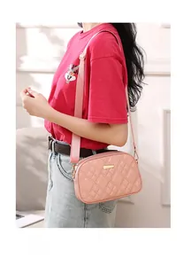 Pink quilted crossbody camera bag with gold hardware and wide adjustable strap detail