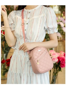Close-up of pink quilted crossbody phone bag with adjustable nylon strap worn by model