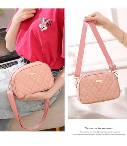 Close-up of pink quilted diamond pattern and metallic decorative plate on camera bag