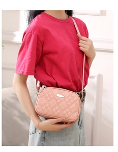 Detailed view of pink quilted crossbody bag with golden metal hardware and embroidery