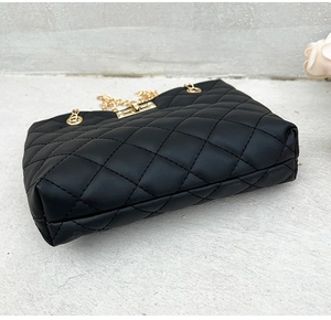 Close-up detail of black quilted rhombus stitching with a gold metal turn-lock on the bag