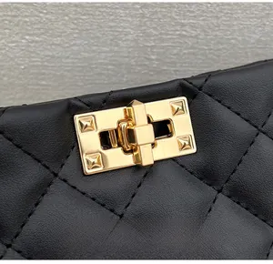 Close-up of golden rectangular twist-lock hardware on black quilted leather handbag