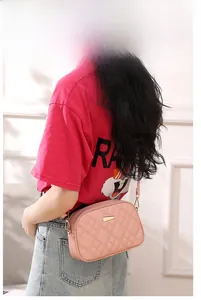 Close-up of a pink quilted crossbody bag with gold metal buckle on a model shoulder