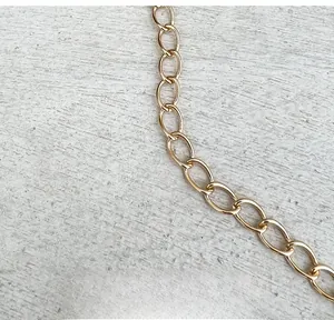 Close-up of light gold metal chain strap with polished oval links for shoulder bag