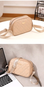 Detail of beige quilted crossbody bag with golden hardware and wide fabric shoulder strap